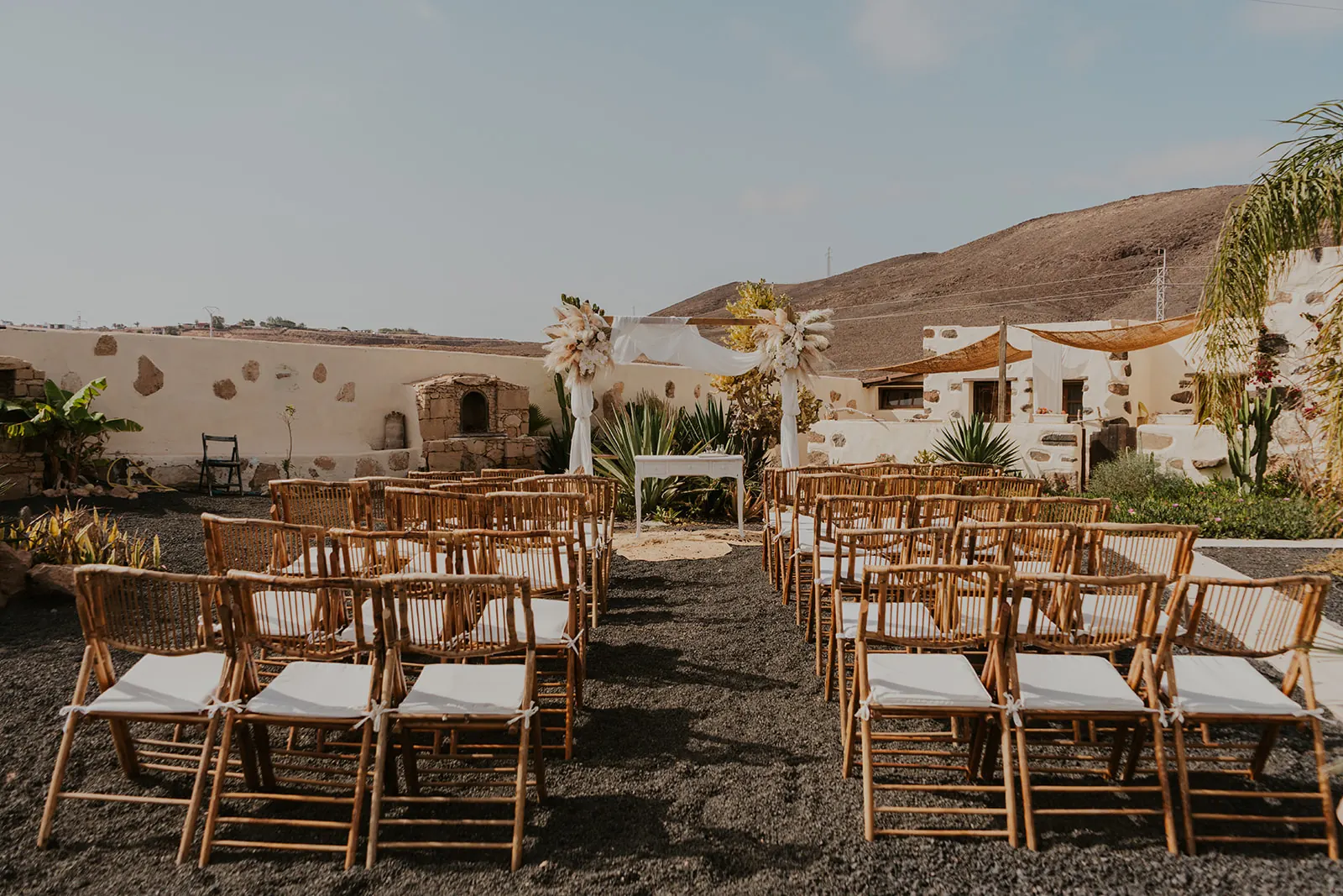 Ceremonia en finca con arco floral blanco y sillas de ratán